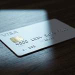 An unbranded payment card half lit and half in shadow, illustrating delegated spending authority in agentic commerce